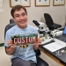 Marek Stanton holding pollinator license plate